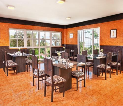 - une salle à manger avec des tables, des chaises et des fenêtres dans l'établissement Mango Hill Kodai, à Kodaikānāl