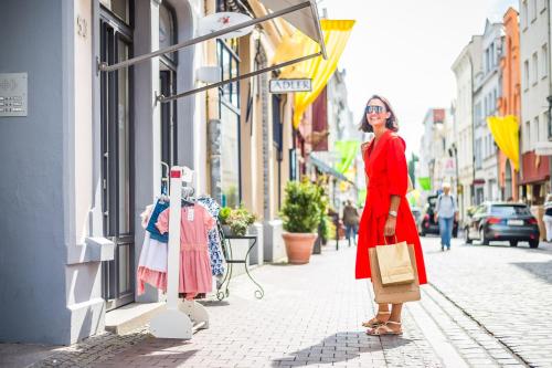 Une femme en robe rouge marchant dans une rue dans l'établissement IntercityHotel Lübeck, à Lübeck