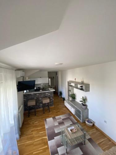 a living room with a table and a kitchen at Apartman Una in Čačak