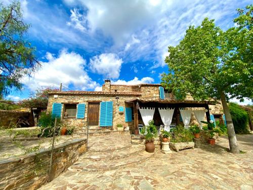 uma casa com persianas azuis e plantas em frente em Casa La Rocita em Badajós