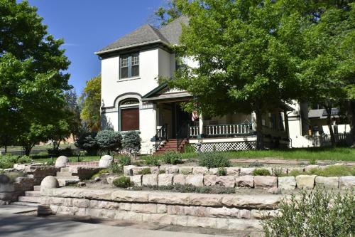 une maison blanche avec un mur en pierre devant elle dans l'établissement Downen House Bed & Breakfast, à Pueblo