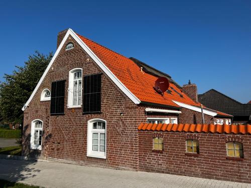 budynek z czerwonej cegły z pomarańczowym dachem w obiekcie Lindenhuus-Urlaub unter einem Teilreetdach-Terrasse - Nahe Norden-Norddeich w mieście Osteel