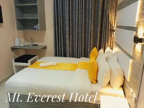 a hotel room with a bed with yellow pillows at Mt. Everest Hotel in Kisii