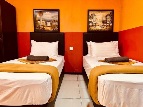 2 Betten in einem Zimmer mit orangefarbenen Wänden in der Unterkunft Smart Budget Hotel - Klang in Klang