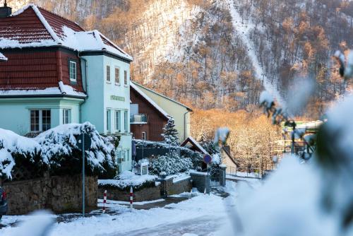 uma casa com neve em frente a uma montanha em Hotel Garni Haus Sonneneck em Thale