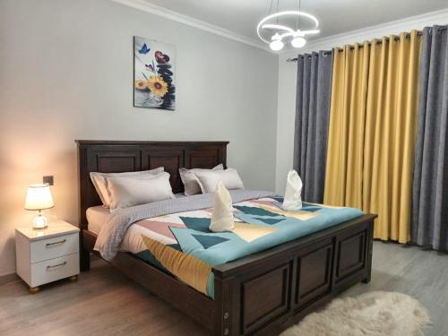 ein Schlafzimmer mit einem großen Bett mit einem Nachttisch und einer Lampe in der Unterkunft New 2 & 3 bedroom Apartment in Kilimani Nairobi with rooftop pool in Nairobi