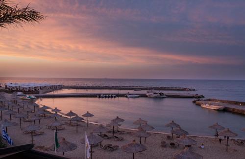 a group of umbrellas on a beach with a pier at Nana Golden Beach All Inclusive Resort & Spa in Hersonissos