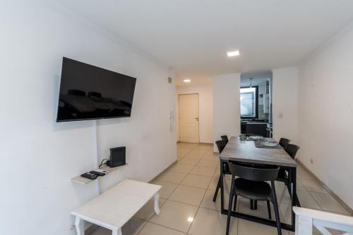 Cette chambre dispose d'une table, de chaises et d'une télévision murale. dans l'établissement Cómodo depto de dos habitaciones by lofty, à Córdoba