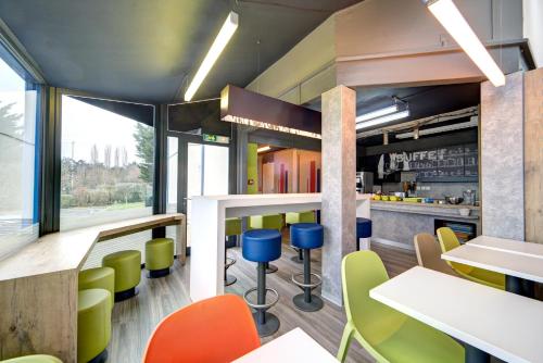 een restaurant met groene en oranje stoelen en tafels bij ibis Budget Caen Memorial in Caen