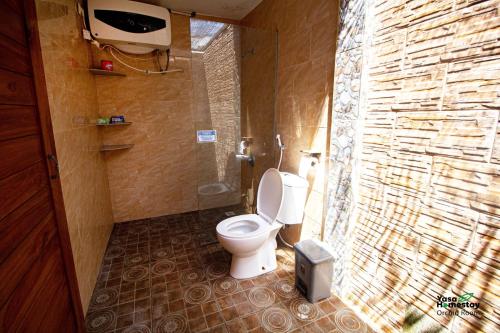 uma casa de banho com um WC e uma parede de pedra em Yasa Homestay em Nusa Penida