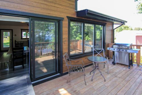 un porche cubierto con parrilla, mesa y sillas en Magnifique chalet au bord du Lac-Saint-Jean, en Roberval