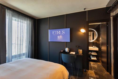 una camera d'albergo con letto e TV a parete di Etrus - Boutique Room & Rooftop a Pontecagnano