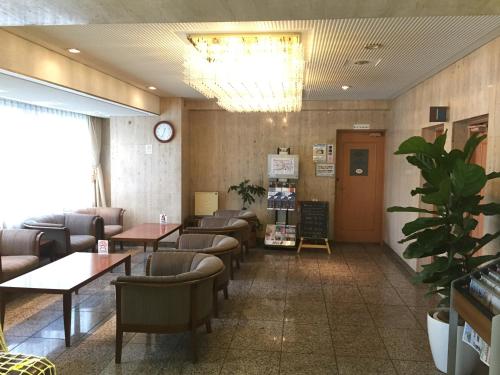 una sala d'attesa con tavoli, sedie e orologio di Sky Heart Hotel Kawasaki a Kawasaki