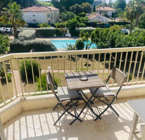 une table et deux chaises assises sur un balcon dans l'établissement Studio de standing climatisé, avec piscine, proche de la mer, à Fréjus