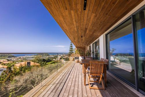 eine Holzterrasse mit einem Tisch und Stühlen auf einem Haus in der Unterkunft Quinta das Camélias - Açores in Ponta Delgada