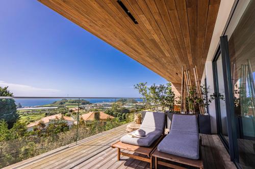 einen Balkon mit Stühlen und Meerblick in der Unterkunft Quinta das Camélias - Açores in Ponta Delgada