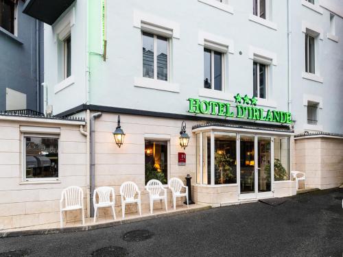 un hotel dunedin con sedie bianche fuori da un edificio di Hôtel Irlande a Lourdes