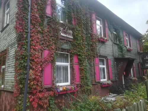 un edificio cubierto de hiedra con puertas y ventanas rosas en Stary Dom, en Augustów