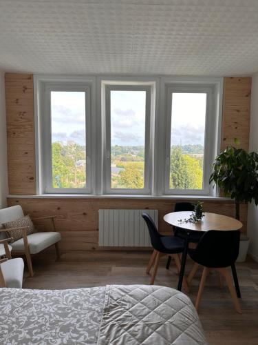 een slaapkamer met 3 ramen en een tafel en stoelen bij Le Petit Port - La Belle Etoile in Sedan