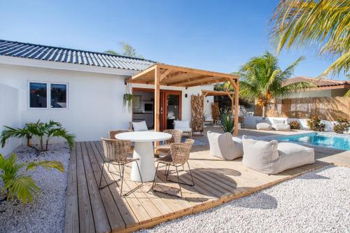 une terrasse avec une table et des chaises à côté d'une maison dans l'établissement Appartement James, à Jan Thiel