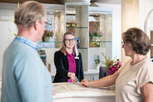 une femme debout au comptoir et parlant à deux personnes dans l'établissement Hotel Ilmenautal inklusive THERMEplus, à Bad Bevensen