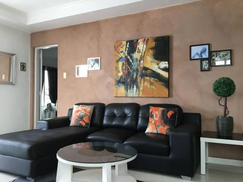 a living room with a black couch and a painting at 2BR condo at Kandi tower 2 in Angeles