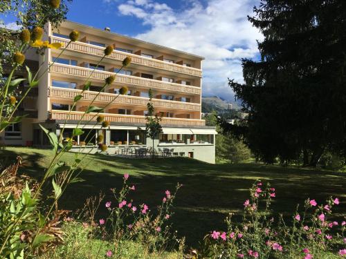 un gran edificio con un jardín delante de él en Hotel Belmont, en Crans-Montana