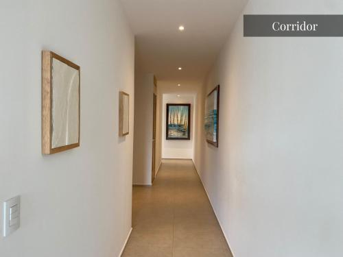 a hallway with white walls and paintings on the walls at Beautiful Aria Ocean 401 QueridaEstancia in Nuevo Vallarta 