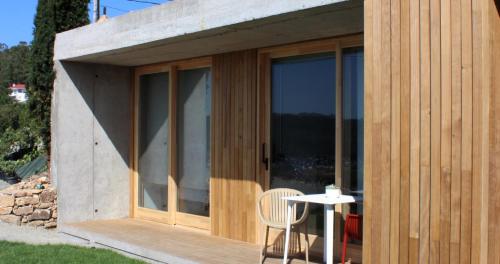 une petite maison avec des portes en verre et une chaise dans l'établissement Doniños Nature, à La Corogne