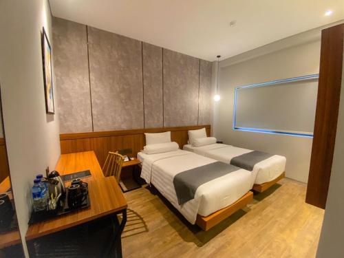 a hotel room with two beds and a desk at Nata Azana Hotel Solo in Solo