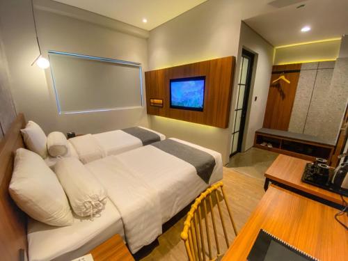 a hotel room with a bed and a television at Nata Azana Hotel Solo in Solo