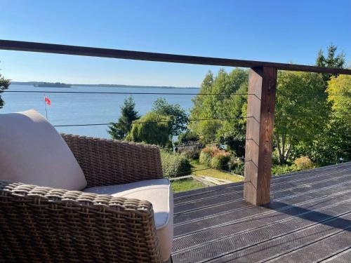 une chaise en osier sur une terrasse avec vue sur l'eau dans l'établissement Apartamenty Fuleda nad jeziorem Dobskim Mazury Holiday, à Fuleda