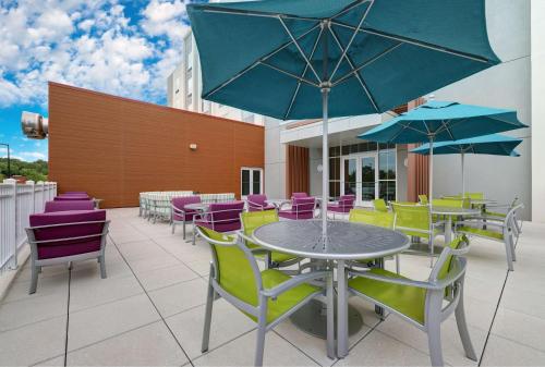 een patio met kleurrijke stoelen, tafels en parasols bij Hilton Garden Inn Manassas in Manassas