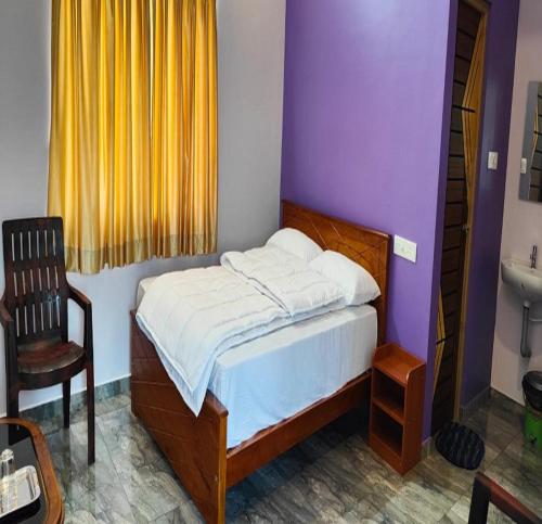 um quarto com uma cama, uma cadeira e um lavatório em Selva Inn em Pondicherry