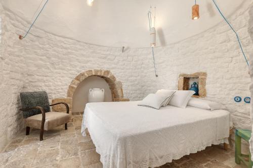 una camera bianca con un letto e una sedia di Trulli Terra Magica a Putignano