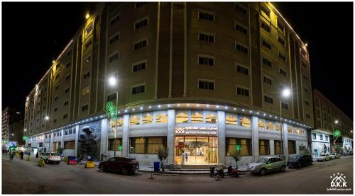 卡尔巴拉Dur Kassir Alkadhimiya Hotel的一座大型建筑,前面有汽车停放