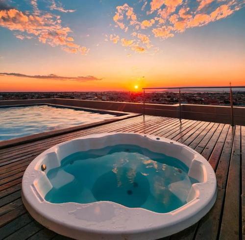 d'une baignoire sur une terrasse avec vue sur le coucher du soleil en arrière-plan. dans l'établissement Paradiso Corporate, à Cabo Frio