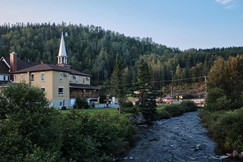 uma igreja e um rio em frente a um edifício em AUBERGE DU DIMANCHE - Hotel - Fjord-du-Saguenay - l'Anse-Saint-Jean - Riviere-Eternite em Riviere Eternite