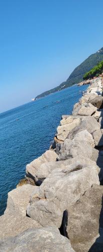 un grupo de rocas junto a un cuerpo de agua en small miramare appartamento sogno sul mare, en Trieste