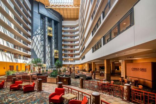 hol hotelu z czerwonymi krzesłami i stołami w obiekcie Embassy Suites by Hilton Albuquerque w Albuquerque