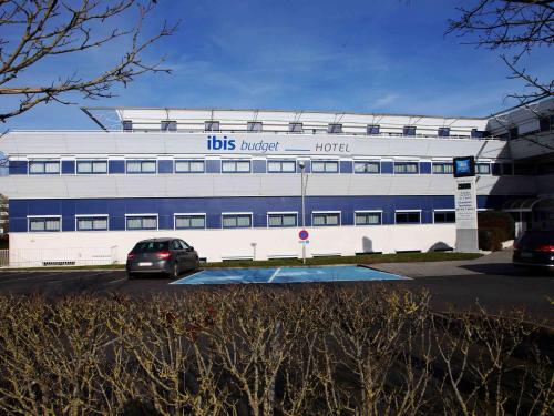 a building with a car parked in front of it at ibis budget Site du Futuroscope in Chasseneuil-du-Poitou