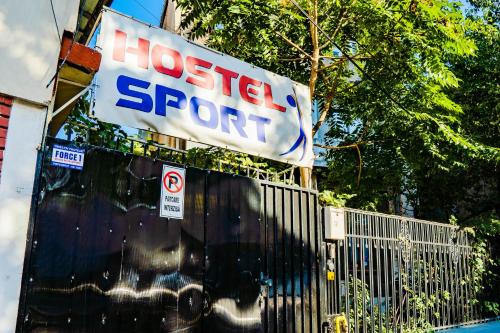 ein Schild, auf dem steht, das Hostel stützt auf einem Zaun in der Unterkunft HOSTEL SPORT BUCHAREST in Bukarest