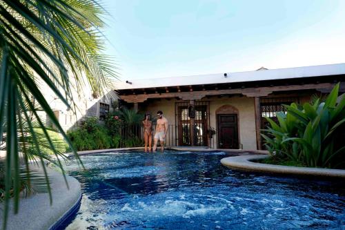 two people standing in a swimming pool in front of a house at Camino Real Antigua in Antigua Guatemala