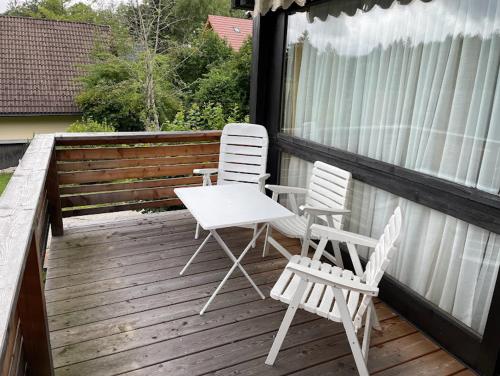 2 chaises et une table sur une terrasse en bois dans l'établissement Ferienwohnung Zirbelweg, à Siegsdorf