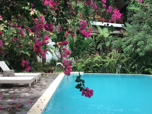 a swimming pool with pink flowers in a garden at Villa Jati Mangsit in Senggigi 