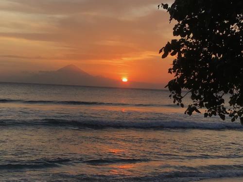 a sunset on the beach with a mountain in the background at Villa Jati Mangsit in Senggigi 