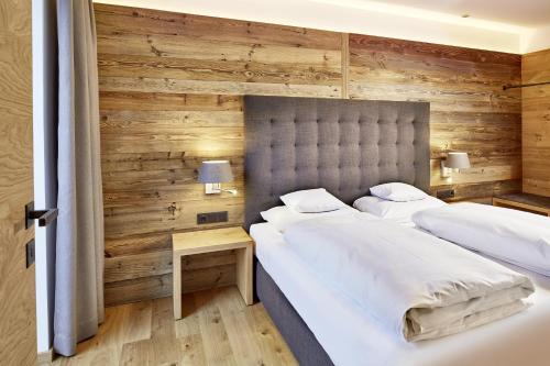 2 camas num quarto com paredes de madeira em der grüne Baum Mountain Boutique Hotel em Ehrwald