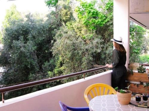 une femme debout sur un balcon donnant sur les arbres dans l'établissement Kalamata's Handmade Apartment, à Kalamata