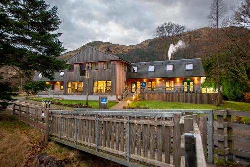 a house with a wooden fence in front of it at Glen Nevis Youth Hostel in Fort William