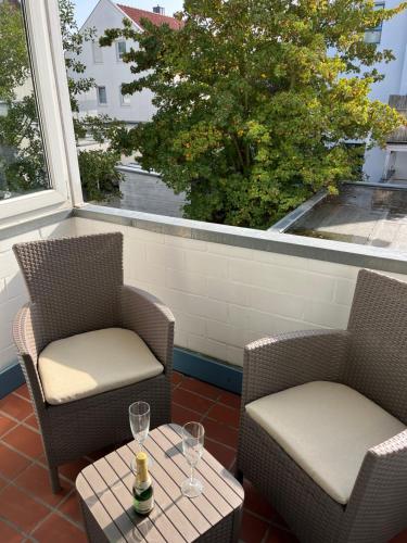 two chairs and a table with wine glasses on a balcony at Ferienwohnung Stadtgracht in Nordhorn